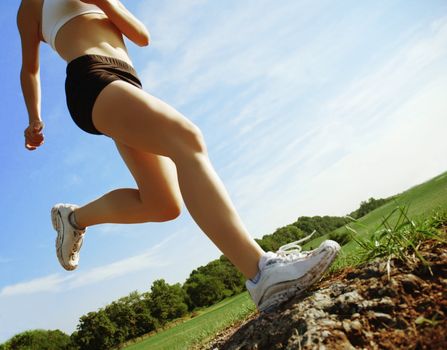 Beautiful woman runner in front of blue sky, low angle.