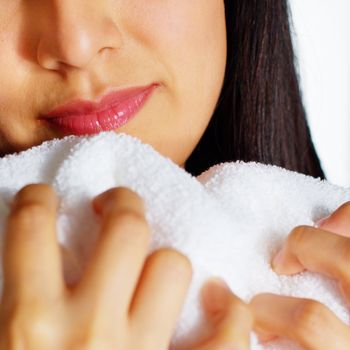 Close up of a woman hugging and smelling a fresh white towel.