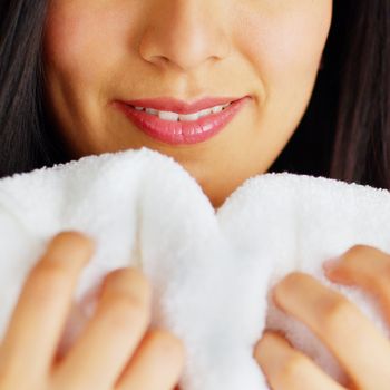 Close up of a woman hugging and smelling a fresh white towel.