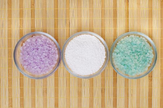 Colored bath salt displayed on top of a bamboo mat.