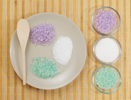 Colorful bath salts on display against a bamboo mat.