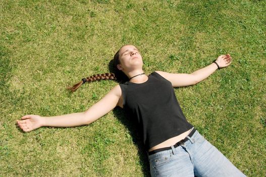 Girl laying on the green grass, relaxing