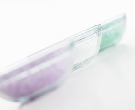 Bowls of colorful bath salt against a white background.