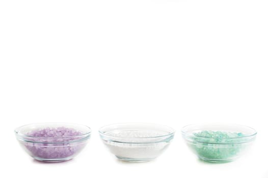Bowls of colorful bath salt against a white background.