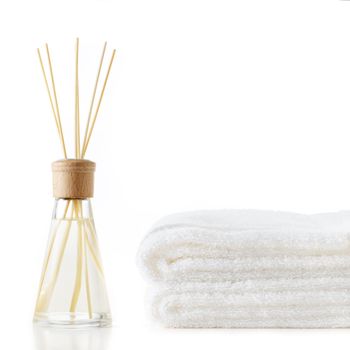 Diffuser and stack of towels against a white background.