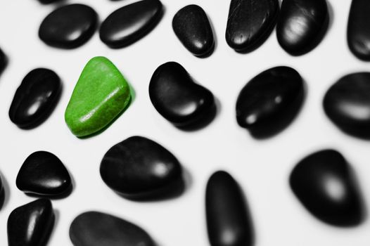 Green rock amid black rocks on a white background.