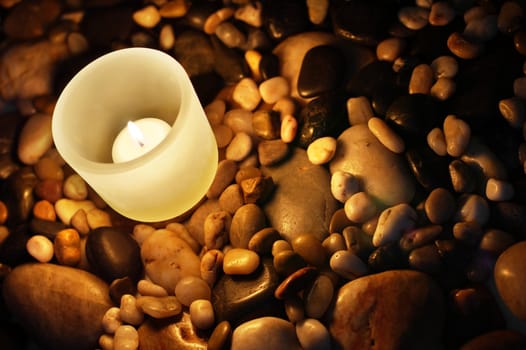 Burning candle on rocks, at night, moody.