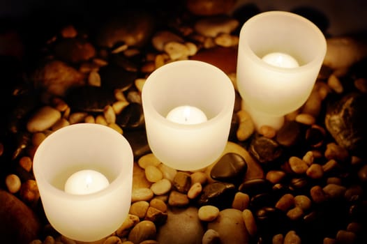 Candels buring at night on top of rocks.