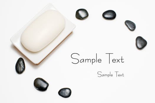 Soap dish and black rocks against a white background.