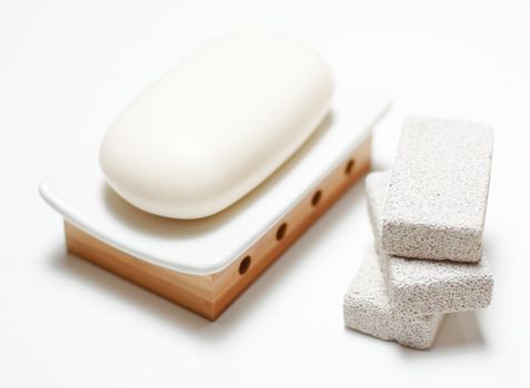 Soap and pumice stones on display, on white.