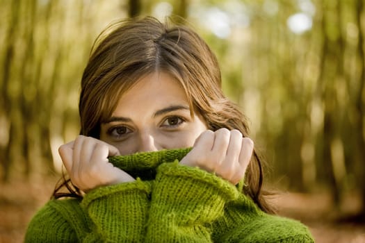 Autumn portrait of a beautiful young woman close to a tree