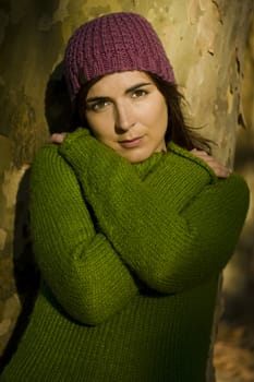 Autumn portrait of a beautiful young woman close to a tree