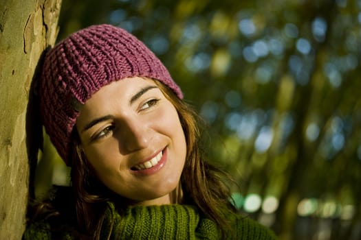 Autumn portrait of a beautiful young woman close to a tree