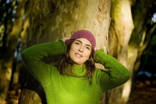 Autumn portrait of a beautiful young woman close to a tree