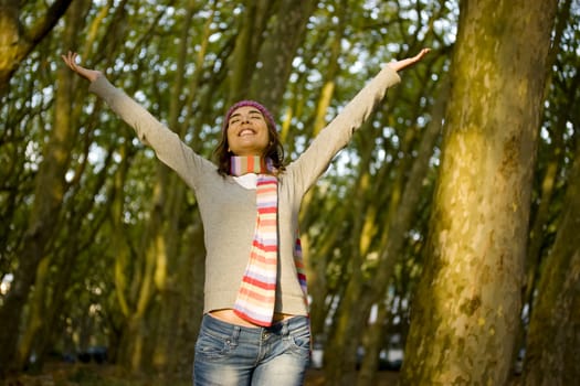 Beautiful happy young woman with open hands in the forest