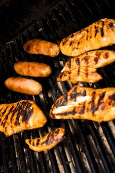 Five pieces of chicken and sausages cooking on the barbeque