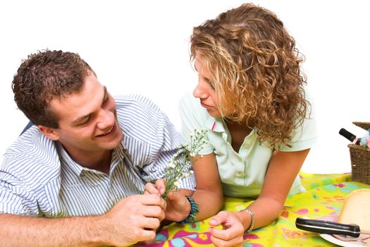 Man giving his girlfriend some fieldflowers during their summer picnic