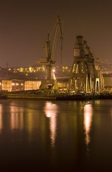 industrial image of cranes and factories at night