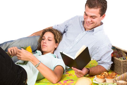 Couple having a picnic and relaxing while the man is reading in a book