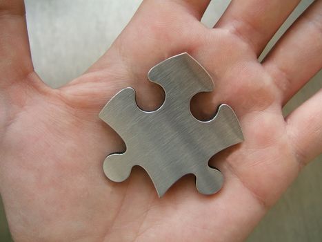 Metallic jigsaw piece in human hand