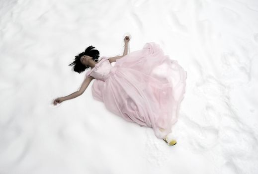 young bride in pink wedding dress resting on the snow