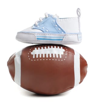 Football with baby shoes against a white background.