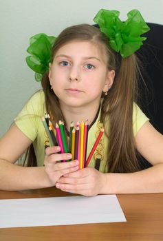 Girl with color pencils in hands and a sheet of paper