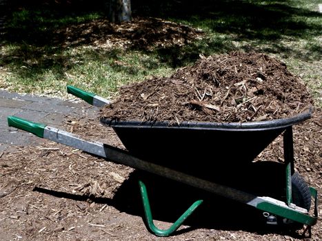 Photo presents gray green wheelbarrow with soil.