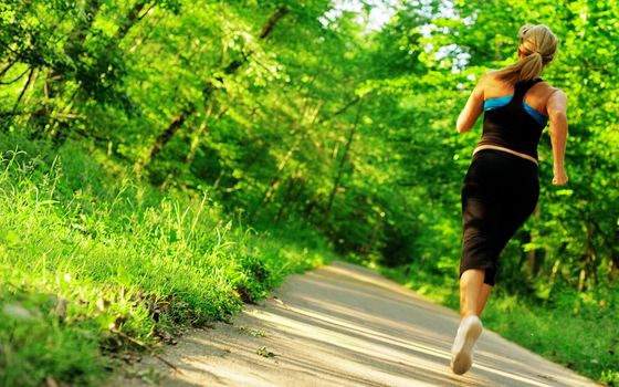 Young woman working out on a forest path.