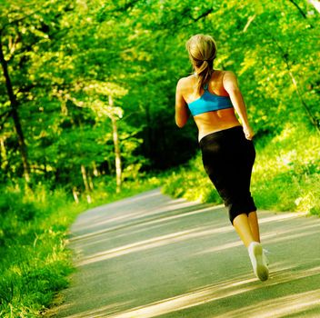 Young woman working out on a forest path.