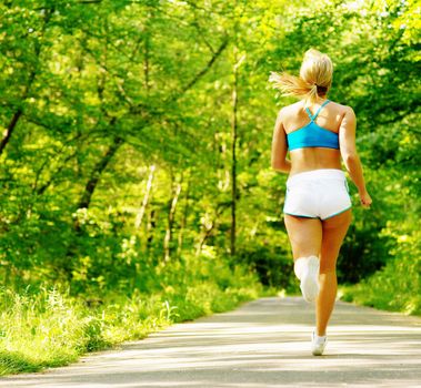 Young woman working out on a forest path.