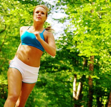 Young woman working out on a forest path.