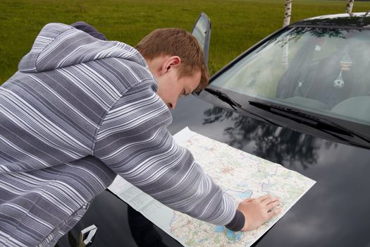 The lost road. The young guy searches for road on a  map