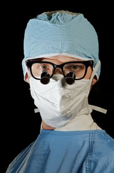 serious surgeon in scrubs and magnifying microsurgery glasses
