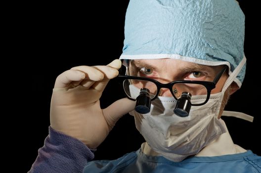 Surgeon looks over magnifying glasses