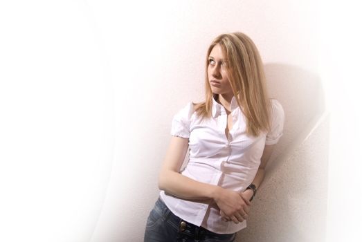 Portrait of a young pretty blonde against the white wall