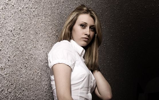 Portrait of a young pretty blonde on the wall background