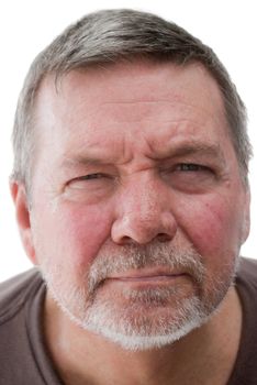Mature man of 58 years, with white stubble, looking straight into the camera and squinting.