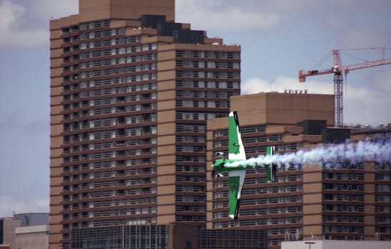 A green plane racing through the city.