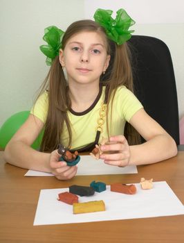 Girl sitting at a table with plasticine in hands