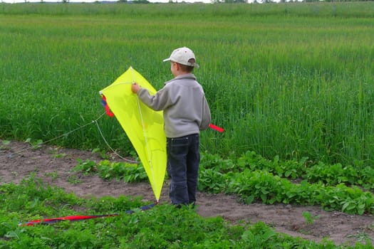 small boy flying a yellow kite