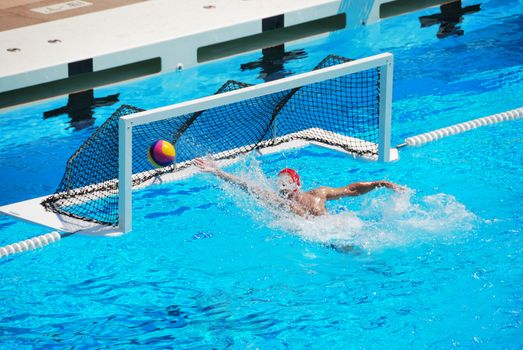 A water polo goalkeeper misses the ball going into the net of the goal.