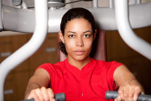 Attractive young woman sitting on a fitness machine working out