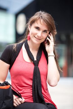 Pretty young woman sitting in shopping center on the phone
