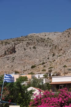 greek scene with national flag and bougainvillea in Kalymnos island port