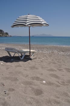 gorgeous beach scene with greek umbrella and chair at Kefalos beach (Kos), Greece