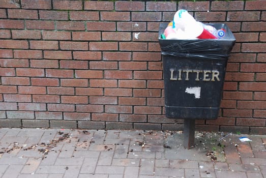 vintage black garbage can on a brick wall background