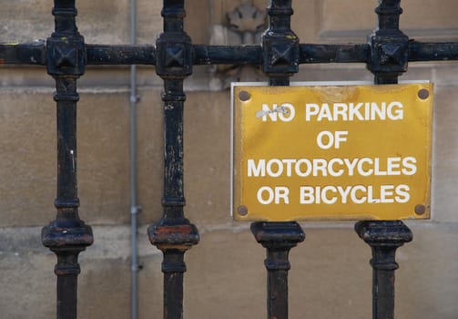 no parking of motorcycles or bicycles golden sign hanging on a metallic fence