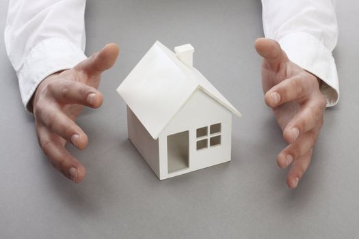 Hands and house model. Real property or insurance concept 