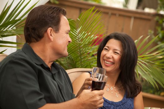 Attractive Hispanic and Caucasian Couple Drinking Wine Outside.